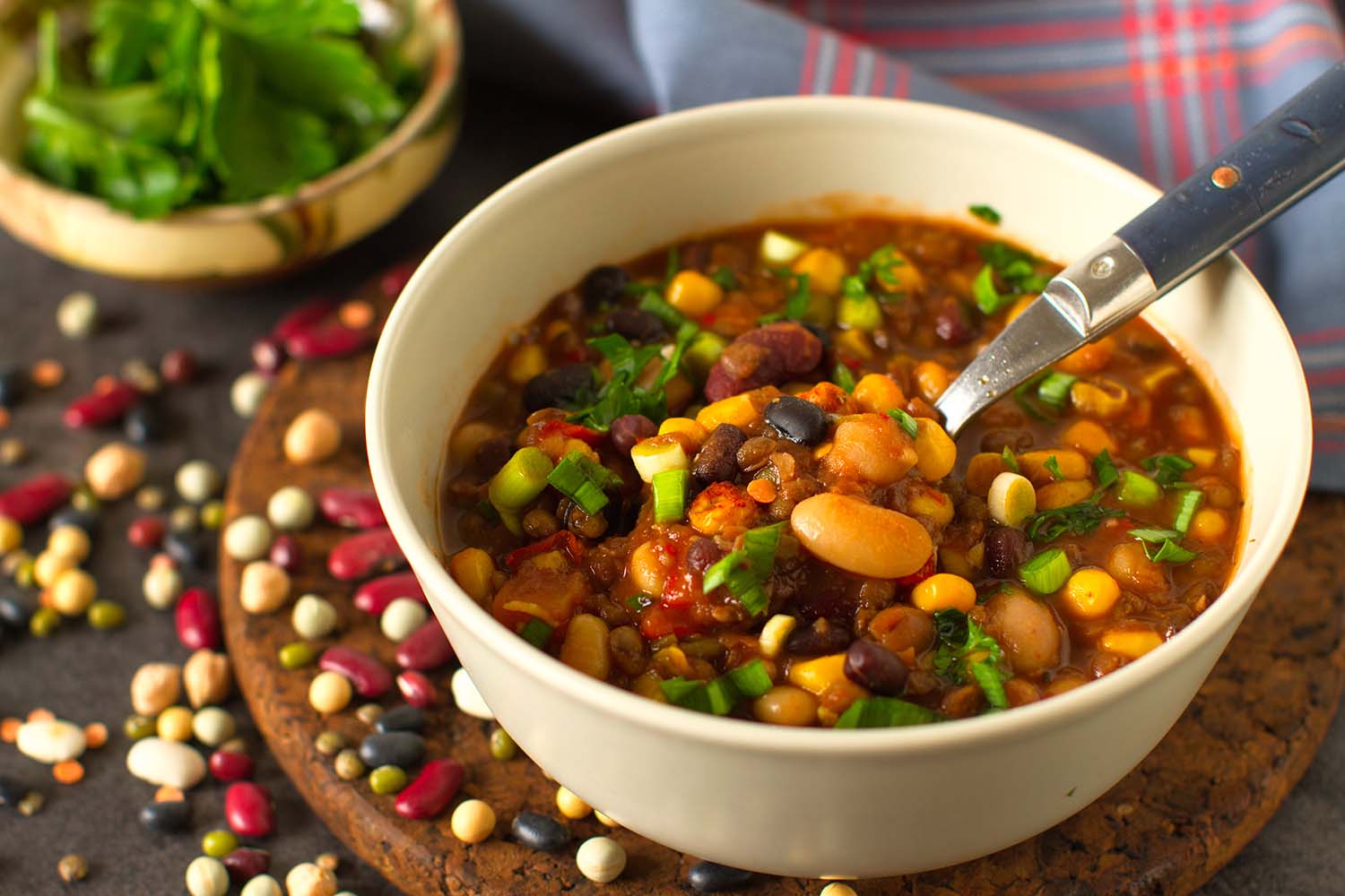 bowl of lentil and bean stew a bowl of lentil and bean stew sitting amidst sprinkled beans, and atop a round wooden cutting board